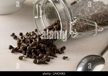 Cumulo di materie, essiccato cannella dei boccioli spice in vetro vaso di storage sul tavolo bianco lo sfondo con il fuoco selettivo Foto Stock