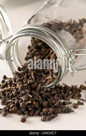 Cumulo di materie, essiccato cannella dei boccioli spice in vetro vaso di storage sul tavolo bianco lo sfondo con il fuoco selettivo Foto Stock
