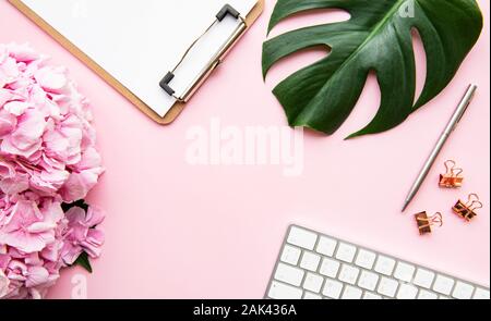 Composizione di bellezza con appunti, ortensie e accessori su sfondo rosa. Vista dall'alto. Lay piatto. Home scrivania femminile. Foto Stock