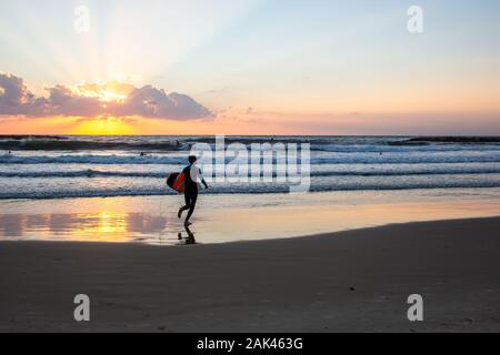 Silhouette di surfisti sulla spiaggia del mar Mediterraneo. Fotografato a Tel Aviv al tramonto Foto Stock