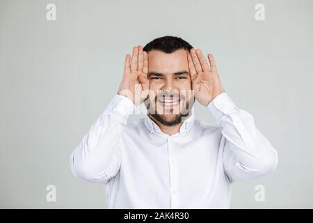 Ritratto di divertenti uomo barbuto ingannare circa su sfondo grigio. l uomo grimaced Foto Stock