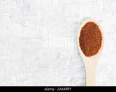 Spezie ed erbe contribuiscono a mantenere in buona salute e a migliorare l'appetito, vista dall'alto sul cemento bianco sullo sfondo. Semi di senape in cucchiaio di legno. Apotheca moderno Foto Stock