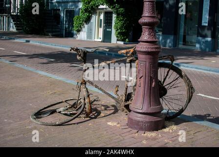 Vecchia bici che ottiene arrugginita parcheggiata nel mezzo della strada Foto Stock