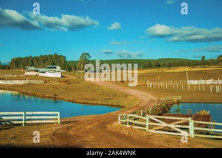 Agriturismo con recinti del bestiame, capannoni e lago blu vicino a Cambara do Sul. Una città con una naturale Attrazioni turistiche nel sud del Brasile. Foto Stock