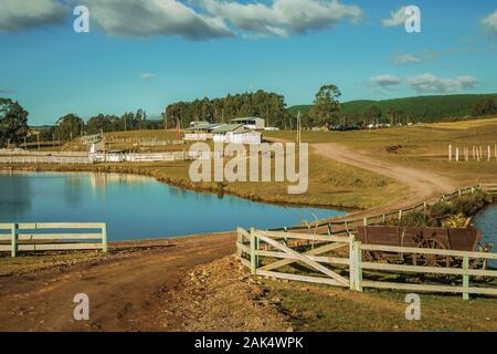 Agriturismo con recinti del bestiame, capannoni e lago blu vicino a Cambara do Sul. Una città con una naturale Attrazioni turistiche nel sud del Brasile. Foto Stock