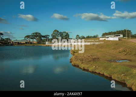 Agriturismo con recinti del bestiame, capannoni e lago blu vicino a Cambara do Sul. Una città con una naturale Attrazioni turistiche nel sud del Brasile. Foto Stock