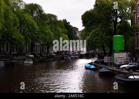 Fiume ad Amsterdam con barche e auto lungo il confine. La giornata è torbida e tranquilla. Foto Stock