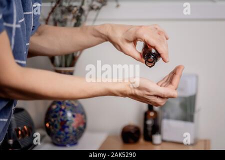 Donna gocce di olio essenziale sul suo palm, mani di persone di mezza età femmina Foto Stock