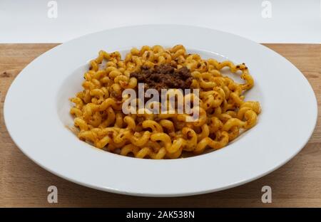 Fusilli lunghi Bucati con ragù alla bolognese su una piastra bianca, un tavolo di legno. Tradizionale pasta italiana Foto Stock