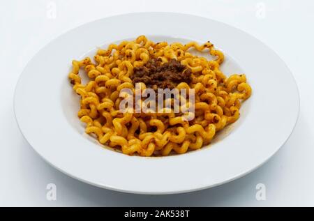 Fusilli lunghi Bucati con ragù alla bolognese su una piastra bianca isolata su bianco. Tradizionale pasta italiana Foto Stock