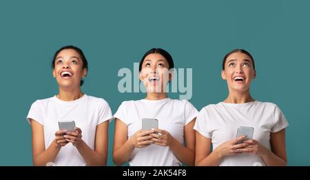 Grande offerta. Tre ragazze millenario azienda vuoto scheda bianca in piedi sopra il Turchese di sfondo per studio. Mockup Foto Stock