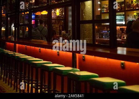 Atene / Grecia, scena notturna da un bar nel centro cittadino. Decorazione Vintage sgabelli verde e l'illuminazione atmosferica. Messa a fuoco selettiva su sgabelli da bar. Foto Stock