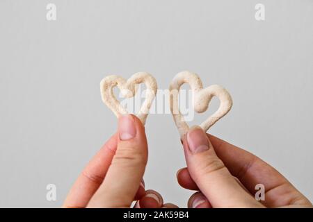 Due a forma di cuore i cookie di meringa in mano Foto Stock