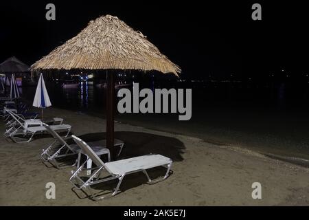 Sedie a sdraio e ombrelloni di paglia ombrelloni. Settembre notte su vuoto spiaggia sabbiosa. Foto Stock