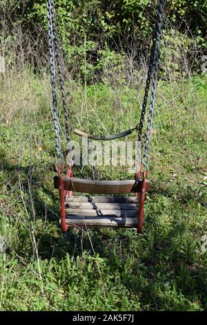 Vecchio swing in giardino ricoperta di abbandono dei giochi. Foto Stock