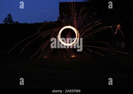 una lunga fotografia di esposizione di una lana d'acciaio sul fuoco che va in cerchi e cadere il ferro sul fuoco ad anello come una doccia Foto Stock