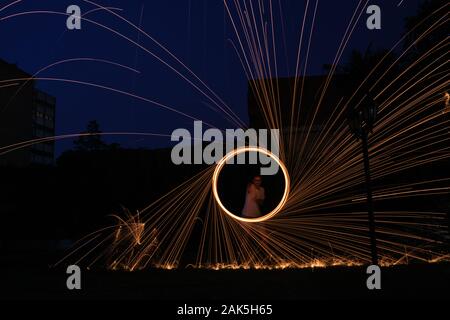 una lunga fotografia di esposizione di una lana d'acciaio sul fuoco che va in cerchi e cadere il ferro sul fuoco ad anello come una doccia Foto Stock