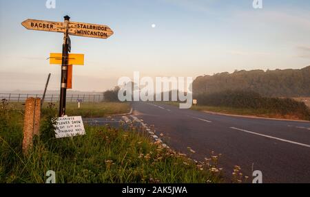 Stalbridge, England, Regno Unito - 15 agosto 2011: Alba sole splende su un fingerpost segno in un vicolo del paese crocevia nelle zone rurali di Dorset. Foto Stock