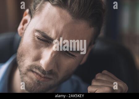 Improvviso mal di testa. Giovane uomo barbuto in maglietta blu sensazione mal di testa Foto Stock