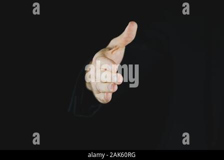 La mano di un imprenditore proveniente da un sfondo nero offre una stretta di mano. Foto Stock