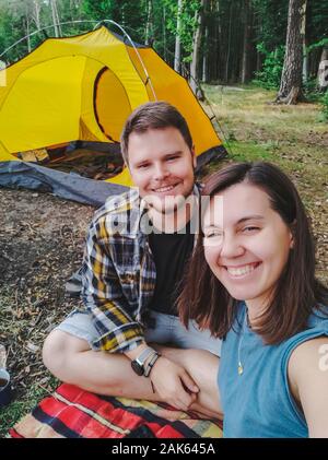 Giovane tenendo selfie picture seduti all'aperto tenda sullo sfondo Foto Stock