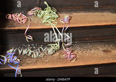 Dopo un party - left overs di coloratissimi coriandoli e nastri di carta su legno passi Foto Stock