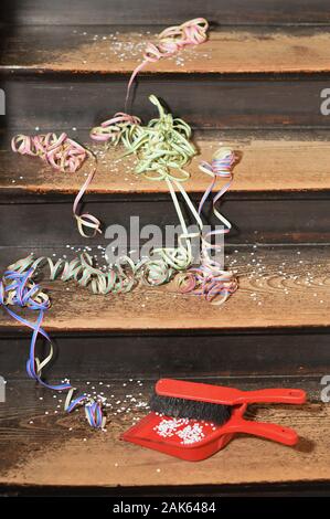 Coriandoli e nastri sui gradini di legno e una scopa con una polvere pan - pulizia dopo la festa Foto Stock