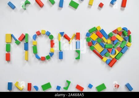 In legno colorato blocchi giocattolo scritte la parola mamma e un cuore su sfondo bianco Foto Stock