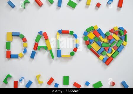 In legno colorato blocchi giocattolo scritte la parola papà e un cuore su sfondo bianco Foto Stock