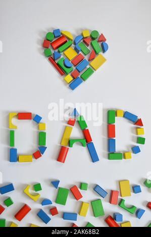 In legno colorato blocchi giocattolo scritte la parola papà e un cuore su sfondo bianco Foto Stock