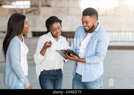 Allegro americano africano giovane rispondendo al questionario del sondaggio intervista all'aperto, sotto forma di riempimento, condividendo il loro parere, spazio libero Foto Stock