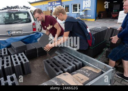 Due ragazzi adolescenti mattoni di caricamento da un negozio di ferramenta cantiere di alimentazione nel rimorchio per la costruzione di un camino. Rzeczyca Polonia centrale Europa Foto Stock