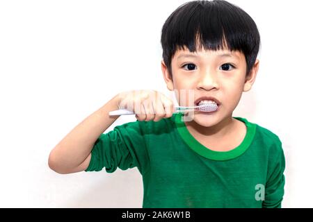 Piccolo ragazzo asiatico con spazzolino da denti la pulizia dei denti isolati su sfondo bianco. Close up kid spazzolando i suoi denti. sanità e igiene dentale concetto. Foto Stock