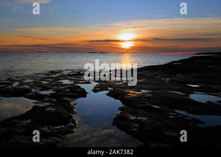 In inverno il tramonto e tidepools a bassa marea sul Lungomare roccioso di Uunisaari Isola, Helsinki, Finlandia. Foto Stock