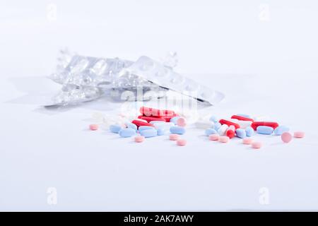 Medicina assortiti di capsule e compresse con un paio di fuori fuoco alveoli vuoti su uno sfondo luminoso. Uso responsabile del concetto di medicinali. Foto Stock