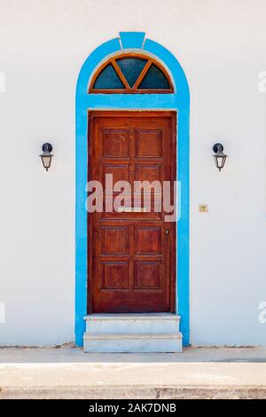 Sfondo della porta. Edificio esterno della porta di legno tra due luci esterne. Parte dell'esterno. Porta vecchia esulla muro grigio. Parte dell'edificio. Parete con sportello sul muro bianco sullo sfondo Foto Stock