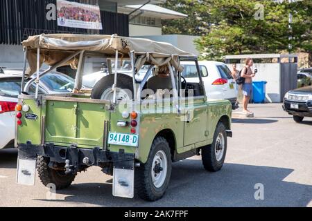 Lady Driving Classic 1976 Land rover difensore serie 1 con soft top accanto alla spiaggia di Sydney, Australia, storico patrimonio nuovo Galles del Sud numberplate Foto Stock