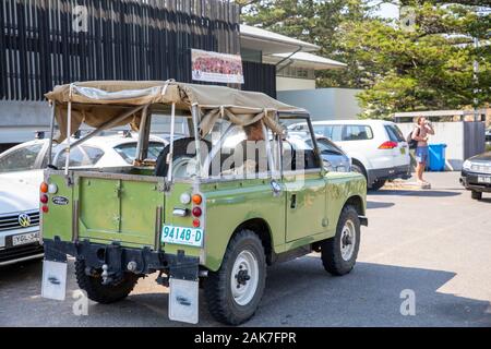 Lady Driving storico 1976 Land rover difensore serie 1 con soft top accanto alla spiaggia di Sydney, Australia, storico patrimonio nuovo Galles del sud numberplate Foto Stock