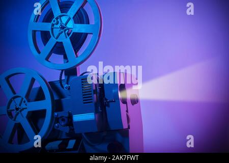 Vintage vecchio proiettore in una stanza buia la proiezione di un film su sfondo al neon Foto Stock