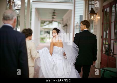 Ritratto di una giovane sposa adulta che cammina con lo sposo e la madre adulta matura. Foto Stock