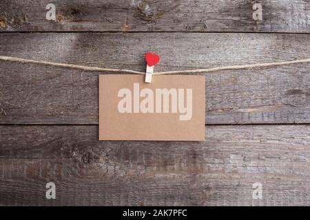 Valentines Day card appeso sul perno con cuore sulla corda sopra lo sfondo di legno, copia spazio per il testo Foto Stock