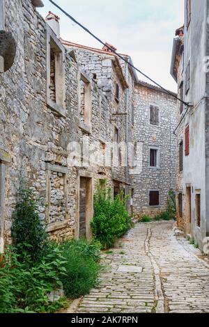 Uno stretto vicolo lastricato tra vecchi edifici nel centro storico della cittadina nella balla, una piccola cittadina collinare sul Mont Pélerin in Istria, Croazia Foto Stock