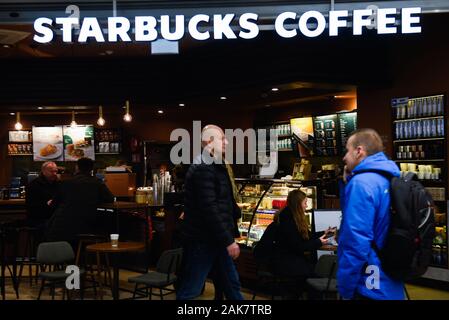 Un uomo passa un negozio Starbucks in Cracovia. Foto Stock