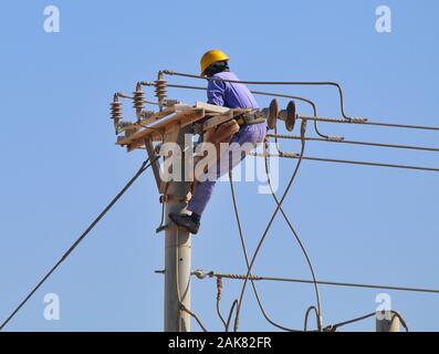 Lavori di manutenzione dell'elettricità in corso di giorno. Questo tipo di lavoro è molto rischioso e dovrebbe essere fatto solo da un dipendente esperto Foto Stock