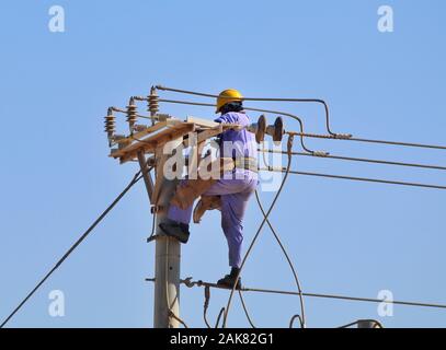 Lavori di manutenzione dell'elettricità in corso di giorno. Questo tipo di lavoro è molto rischioso e dovrebbe essere fatto solo da un dipendente esperto Foto Stock