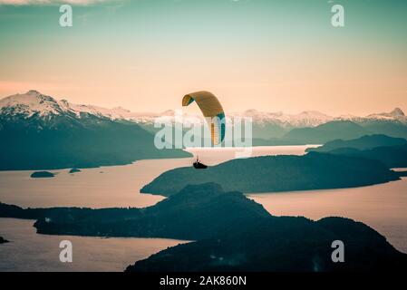 Parapendio oltre Nahuel Huapi lago e montagne di Bariloche in Argentina, con vette innevate sullo sfondo. Concetto di libertà, avventura, battenti Foto Stock