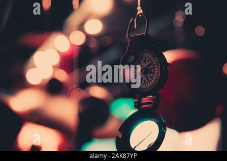 Bellissimo bokeh di fondo di una bussola appeso con luci e riflessioni in background. Concetto di essere perduti, libertà e ricerca della felicità. Foto Stock