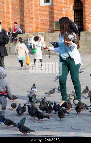 Una donna di alimentare i piccioni e posa per selfies in Piazza San Marco a Venezia Italia Foto Stock