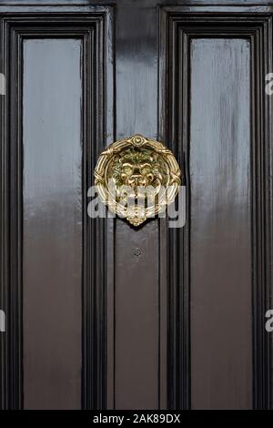 Ottone testa Leone porta respingente su un nero porta di casa. Londra, Inghilterra Foto Stock