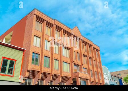 Esterno di un edificio a più piani con pareti in mattoni rossi e alte finestre di vetro Foto Stock